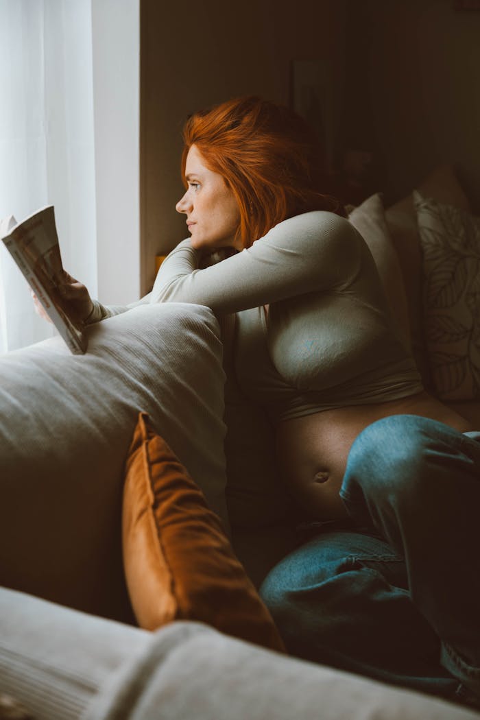gallery-2 Pregnant woman in cozy setting reading, showcasing warm tones and introspection.