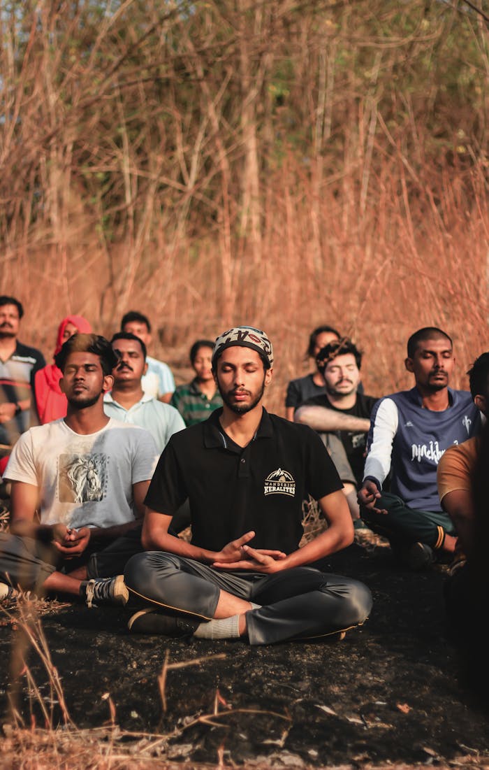 hero-img-02 A diverse group meditating outdoors in a natural setting in Thrissur, India, promoting peace and relaxation.